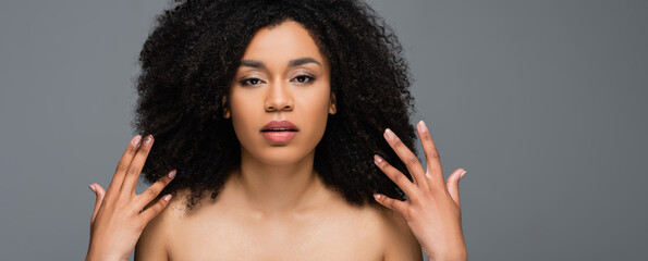 young african american woman with naked shoulders and perfect skin looking at camera isolated on...