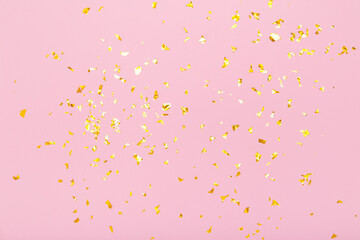 Golden glitter confetti sparkles on pastel pink background. Holiday, festive, party backdrop. Flat lay, top view, copy space