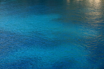 Türkisblaues Meer mit helleren und dunkleren Bereichen und goldener Reflexion Querformat