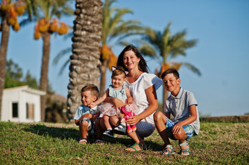 Mother with three kids on Turkey resort against palms.