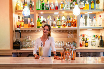 Attractive woman holding a glass with fruit juice looking at camera and smiling
