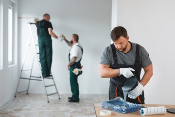 Professional renovation crew painting walls of new build apartment - 465364442