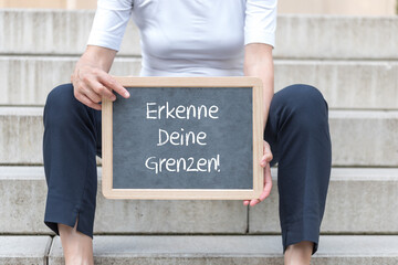 Frau sitzend auf einer Treppe mit einer Tafel auf der 