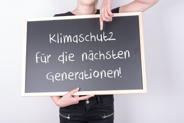 Schülerin oder Jugendliche mit einer Tafel auf der Klimaschutz für die nächsten Generationen steht