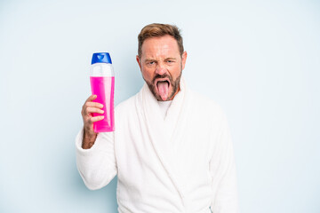 middle age man feeling disgusted and irritated and tongue out. shampoo bottle