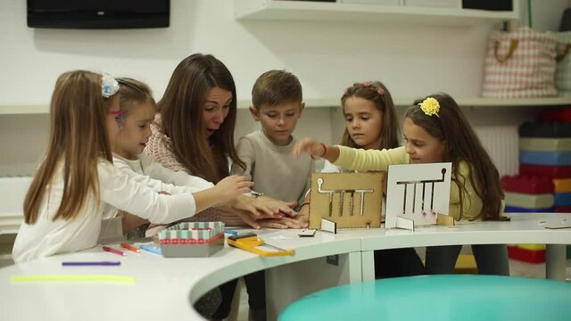 Group of little kids playing with preschool wooden educational toys with kindergarten teacher