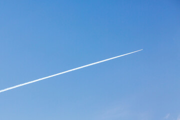 The trace of the plane in the blue sky. The plane is flying high in the sky