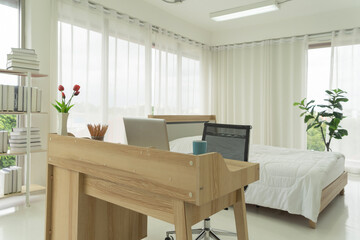 Bedroom at home with a bed and computer notebook laptop on desk. Interior design decoration. Working from home space. Lifestyle.