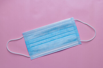 Blue face mask on a pink background. Covid 19 face mask. Corona virus. High quality photo in pastel colours.
