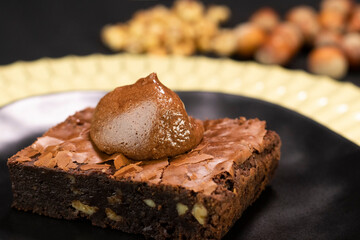Chocolate Brownie with nuts and chocolate cream on black plate