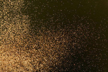 Gold and bronze glitter color confetti dots splash on black. Abstract glow shiny background.
