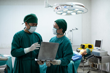 Doctors or surgeons with Physician assistant standing to discussion about a patient case in an...