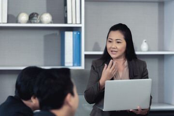 Professional businesswoman or marketologist making presentation and coaching to her colleagues with laptop in office during business meeting