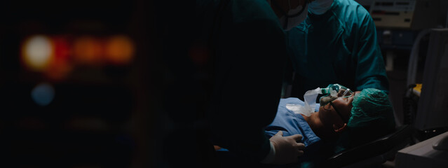 Patient wear a medical ventilator lying on the surgical bed in the operating room with surgeon stand by his side to keep an eye on the symptoms at hospital in night time in banner with copy space © KL 1981