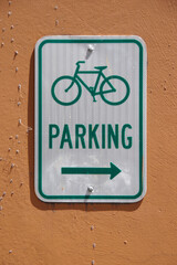 Green and white BICYCLE PARKING sign on a building wall