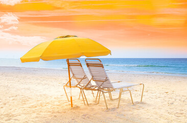 Beach chairs with umbrella at the ocean with yellow sky