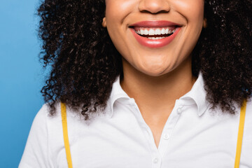 close up view of cropped african american woman smiling isolated on blue