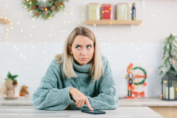 Beautiful lonely depressed woman left alone on Christmas Eve, sadly looking at the phone