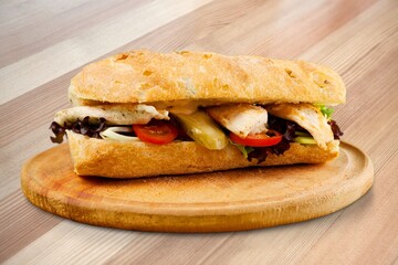 Yummy baguette sandwich with various vegetables and slices of cheese on the desk