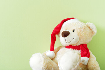 Teddy bear with red cap against light green background
