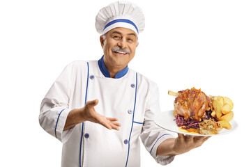 Cheerful mature chef smiling and holding a plate with a meat dish and potatoes