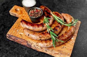 grilled sausages with spices on a stone background 