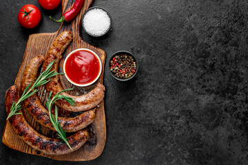 grilled sausages with spices on a stone background with copy space for your text