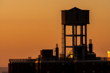 Urban water tower at sunset (golden hour) in Brooklyn, New York.