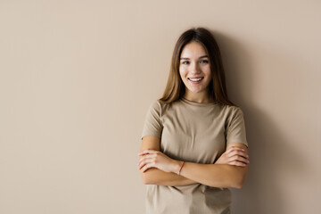 Obraz premium Charming woman standing with hands folded, looking at camera, isolated over beige background