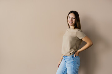 Portrait of a smiling young woman posing isolated over beige background