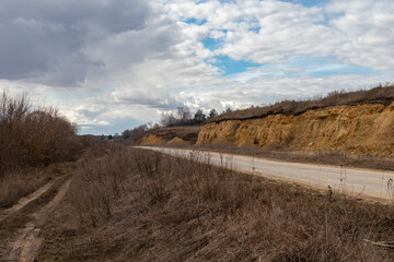 rural road near limestone rocks under a gloomy sky in early spring