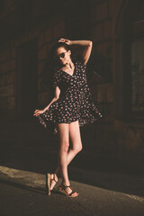 Portrait of stylish young woman. Brunette with curly hair in sundress posing on street. selective focus