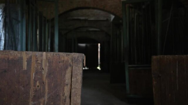 One sash of a wooden gate in a dark deserted barn opening wide
