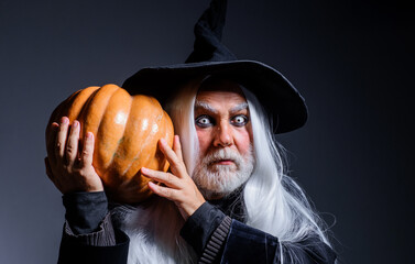 Devil vampire with Jack-o-lantern. Halloween man in witch hat with pumpkin.