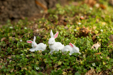 Cute Easter bunny figurine on a green moss of the forest ground. Spring seasonal Easter holiday background