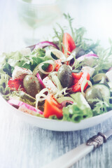 Salad with Green Olives, Tomatoes and Feta Cheese. Bright wooden background. Close up. 