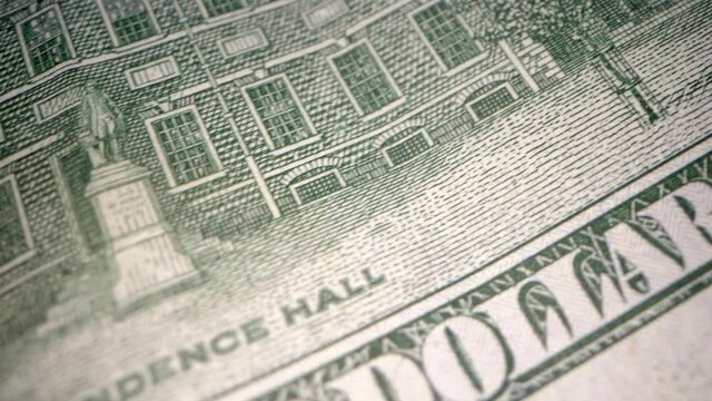 This ultra close up, panning video shows a macro view of the backside of a one hundred dollar bill.