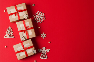 Christmas gifts kraft boxes with red ribbon and eco-friendly wooden Christmas tree toys on a red background. The concept of Christmas, New Year background with copying space