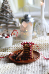 Stack of chocolate chip cookies tied with ribbon, cinnamon, anise, various Christmas decorations and lit candles. Hygge at home. Selective focus.