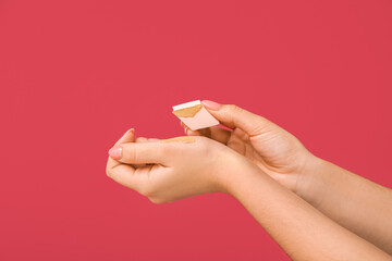 Woman putting foundation with makeup sponge on her wrist on color background