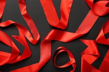 Shiny red ribbons on dark background, closeup