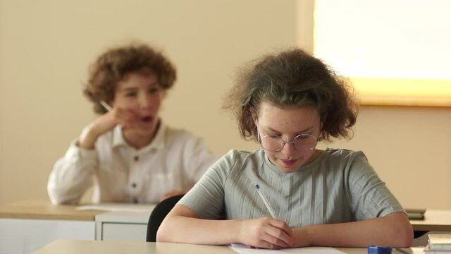 Back to school. Schoolgirl cheats during the test at school. The stern teacher walks over and takes the clues. School exams concept