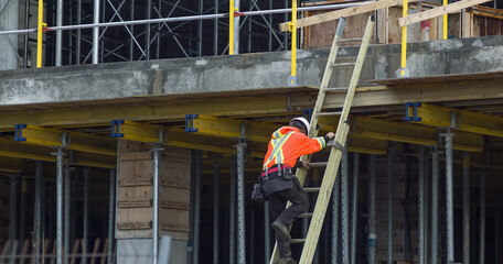 worker in ladder construction site metal and concrete structure hard hat professional