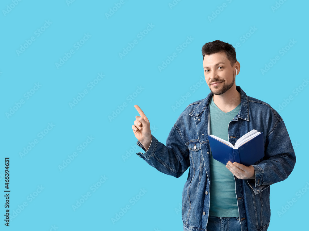 Poster man with earphones and book pointing at something on color background