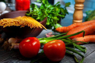 long semolina noodles in a wooden bowl with assorted vegetables eggs on table and light from a window