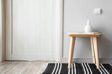 Decorative pineapple with magazine on table near light wall