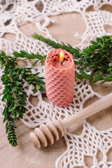 Lighted pink beeswax candle on wooden background. Honey aroma