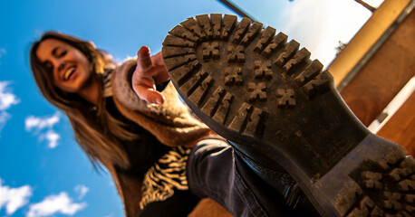 Beauty model girl smiling and posing with a blue sky and brown jacket and black 80's trousers 