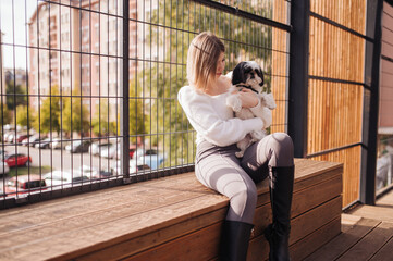 Young girl with her dog walks in a modern park. During the autumn day, enjoy the beautiful weather.