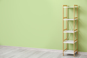 Stylish wooden shelf unit near green wall in room